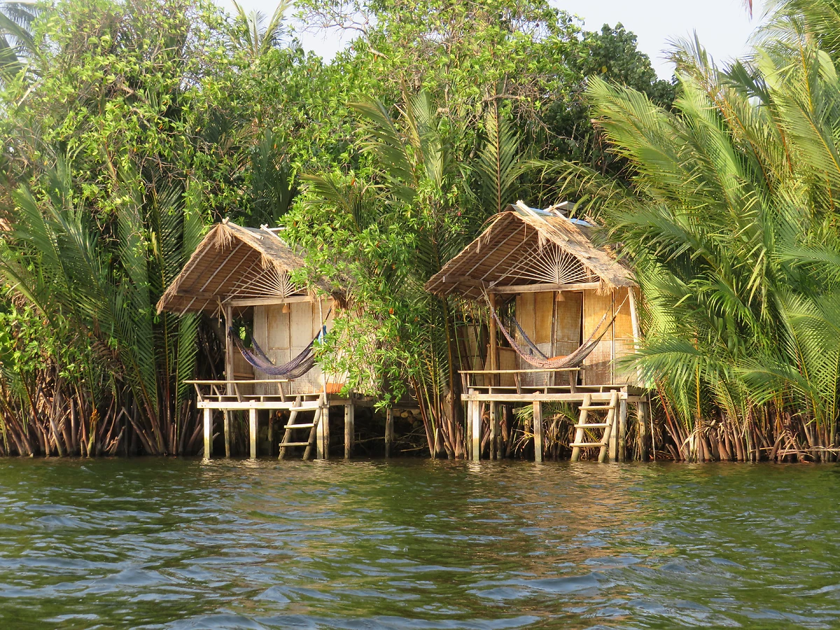 Deux huttes en bois de chaume sur la rivière Praek Tuek Chhu à Kampot, Cambodge