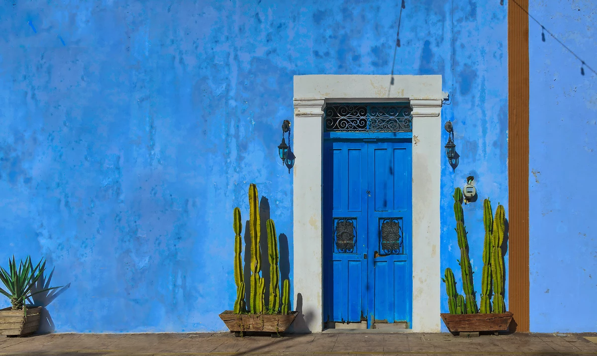 Façade de maison typique peinte en bleu vif avec des cactus près de la porte, Campeche, Mexique
